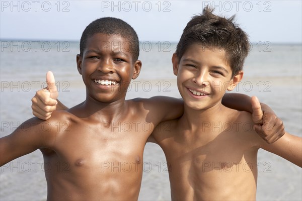 Boys on beach giving the thumbs up sign