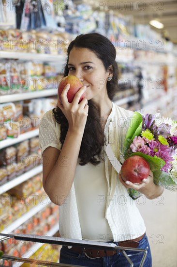 Hispanic woman smelling fruit in grocery store