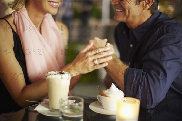 Couple holding hands over coffee in restaurant