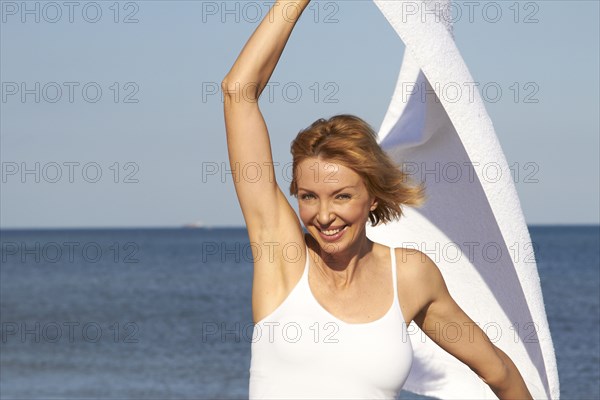 Caucasian woman playing with scarf on beach