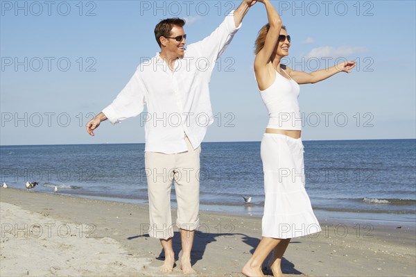 Caucasian couple dancing on beach