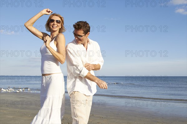 Caucasian couple dancing on beach