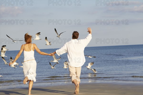 Caucasian couple running on beach