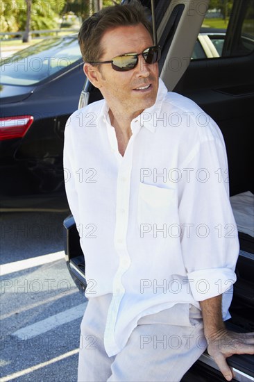 Caucasian man sitting in trunk of car