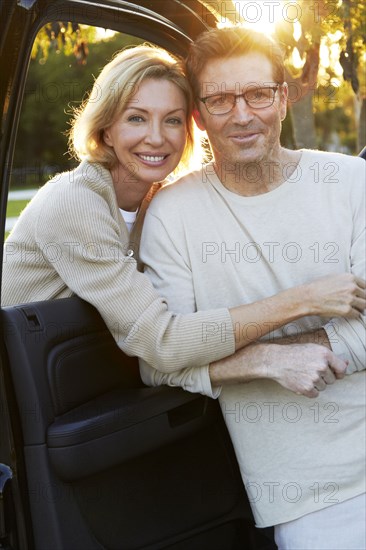 Caucasian couple smiling by car