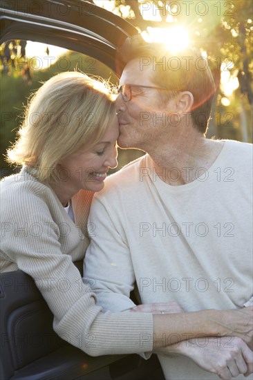 Caucasian couple kissing by car