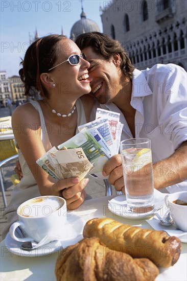 Couple with wads of cash having breakfast at cafe