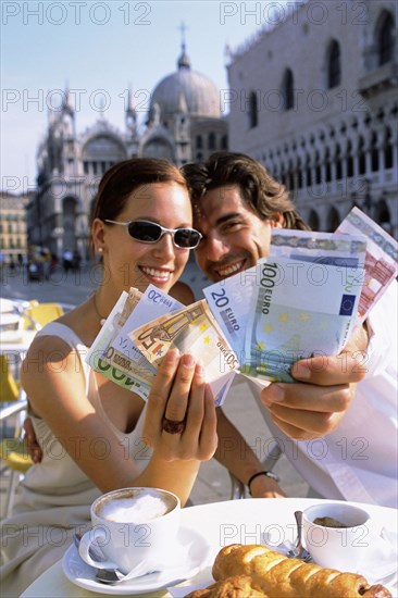 Couple with wads of cash having breakfast at cafe