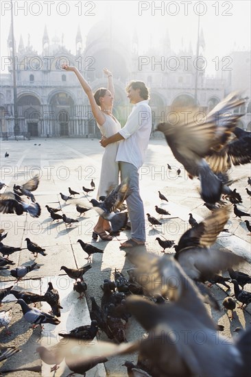 Couple surrounded by pigeons in St. Mark's Square