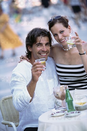 Couple toasting each other at sidewalk cafe