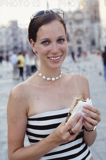 Woman eating sandwich on city street