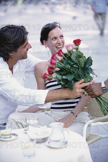 Man buying flowers for girlfriend at sidewalk cafe