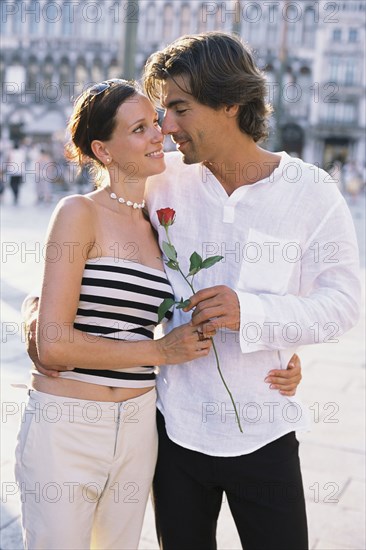 Man giving girlfriend flower on city street