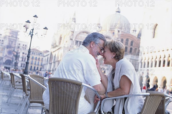 Senior couple touching foreheads at sidewalk cafe