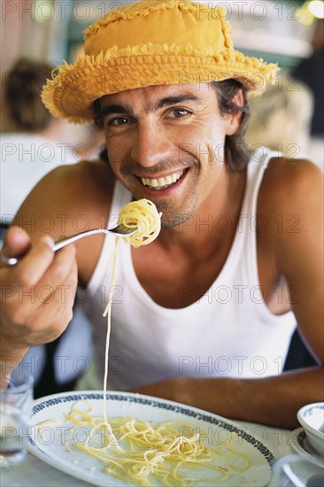 Man eating pasta at sidewalk cafe