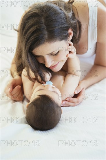 Mother playing with baby on bed