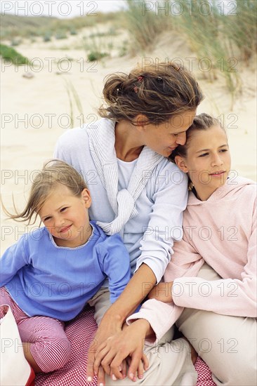 Caucasian mother and daughters hugging on beach