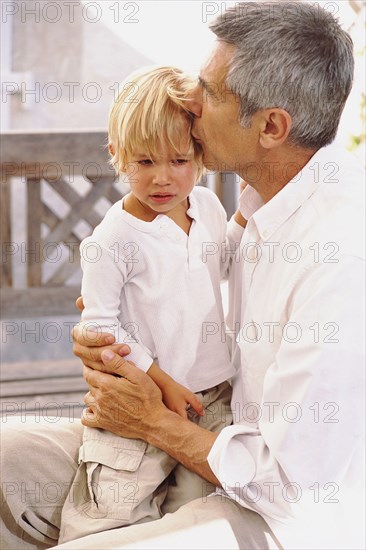 Caucasian father kissing crying son outdoors
