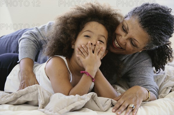 Senior woman and granddaughter laughing on bed