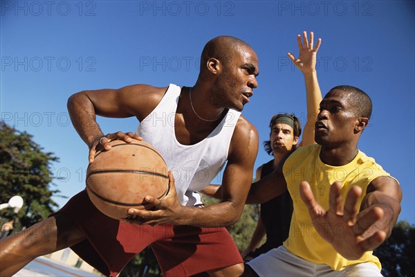 Men playing basketball outdoors