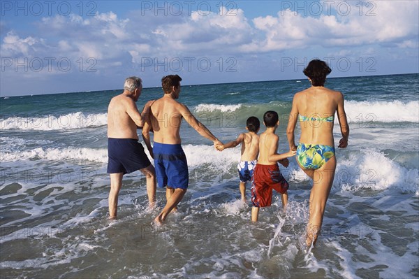 Family walking in waves on beach