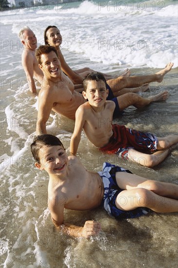 Family sitting in waves on beach