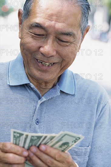Senior man counting money outdoors
