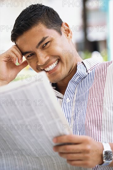 Smiling man reading newspaper