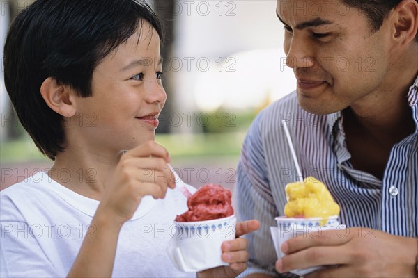 Father and son eating ice cream outdoors