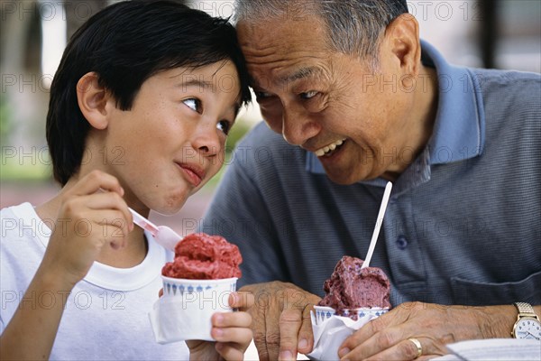 Senior man and grandson eating ice cream outdoors