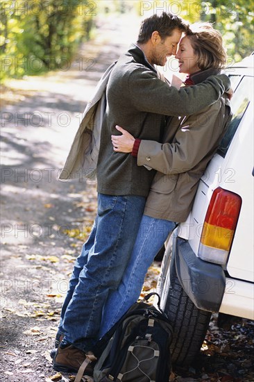 Couple hugging by car