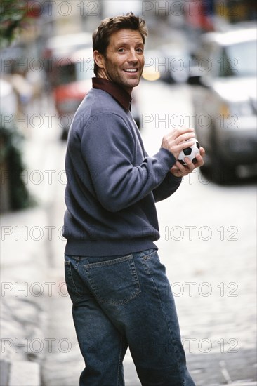 Man holding ball on city street