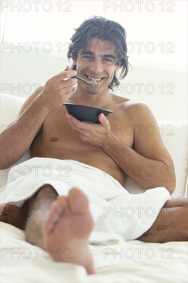 Man eating cereal in bed