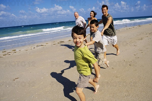 Caucasian family running on beach