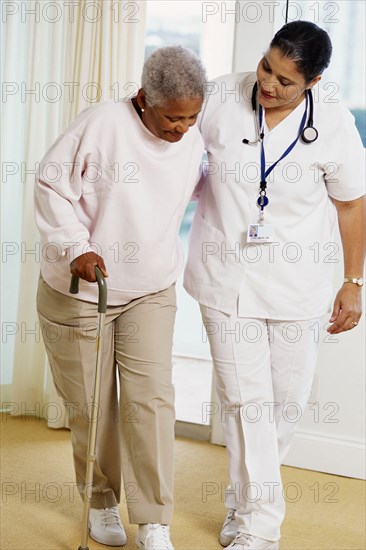 Nurse helping patient use cane