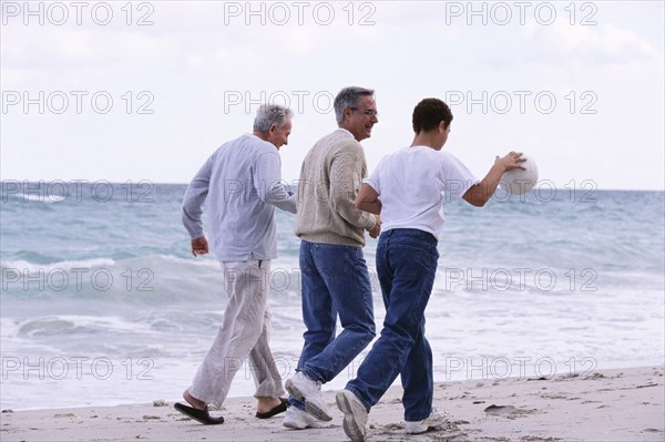 Three generations of Caucasian men walking on beach