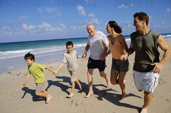 Caucasian family holding hands on beach