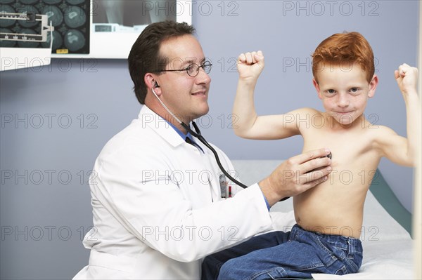 Doctor listening to boy's heartbeat in office