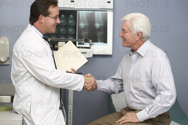 Doctor shaking patient's hand in hospital room