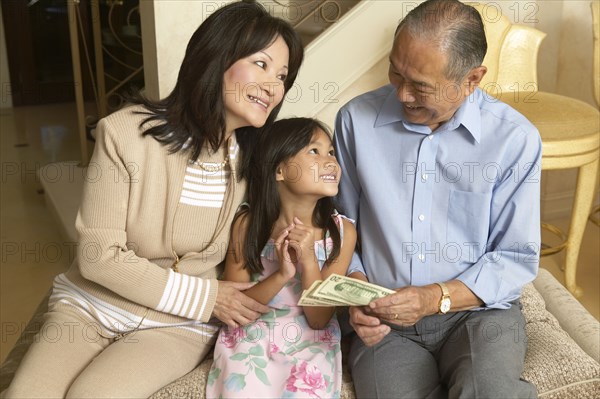 Senior couple giving granddaughter money