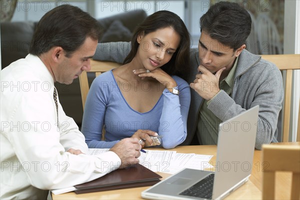 Couple and businessman examining papers