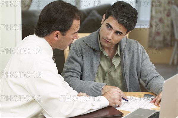 Hispanic man and businessman examining papers