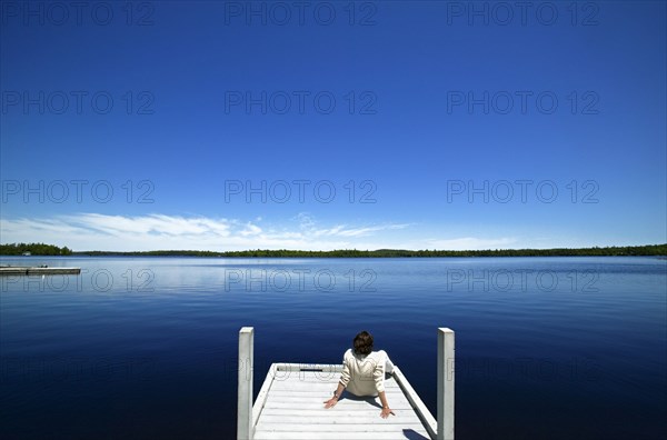 Woman overlooking lake on wooden dock