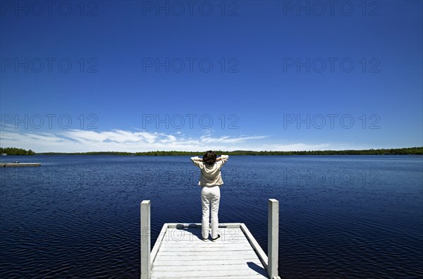 Woman overlooking lake on wooden dock