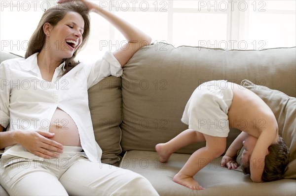 Pregnant mother and son playing on sofa