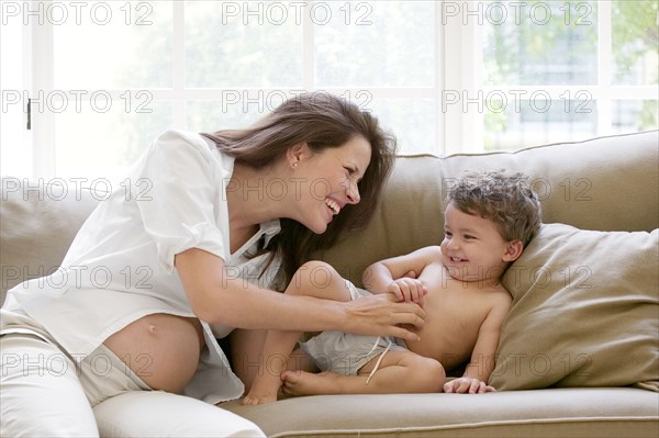 Pregnant mother and son playing on sofa