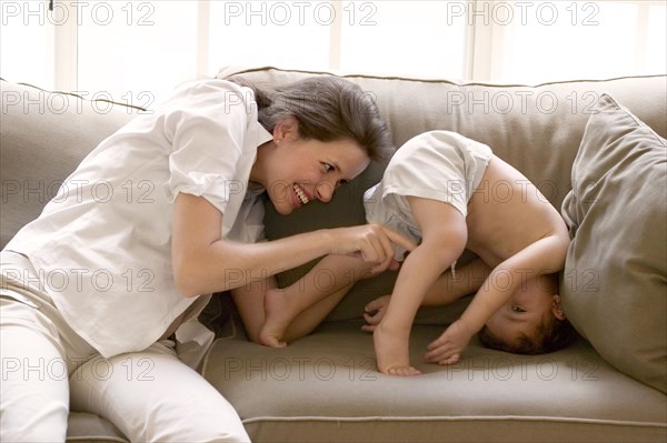 Pregnant mother and son playing on sofa