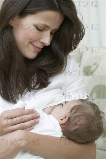 Mother breastfeeding baby on sofa