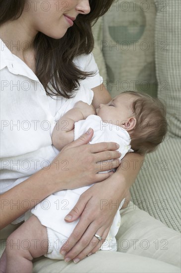 Mother breastfeeding baby on sofa