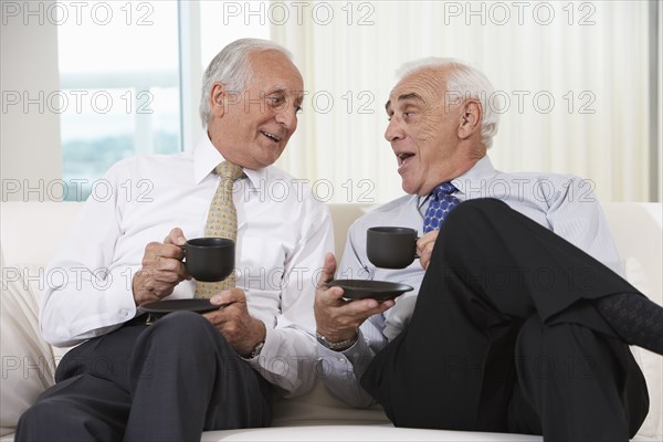 Senior businessmen having coffee on sofa